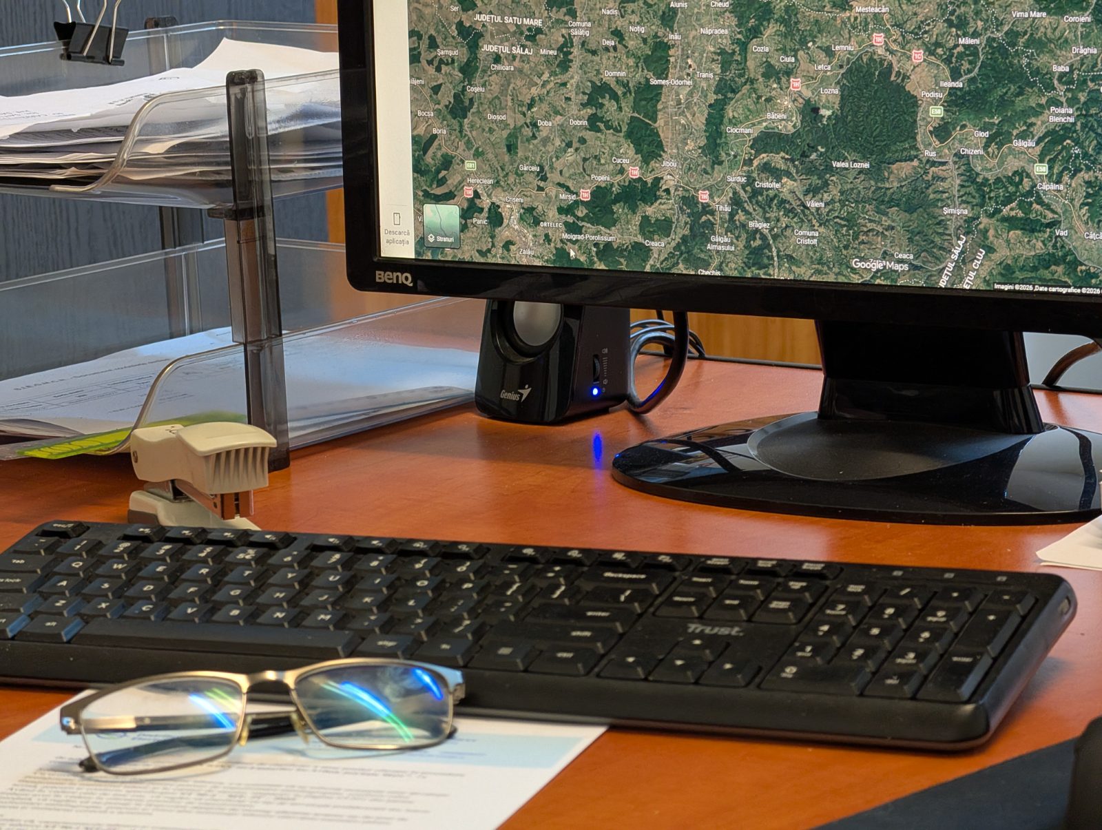 Birou de proiectare Comenerg: monitor cu harta zonei, documentație și ochelari pe masă